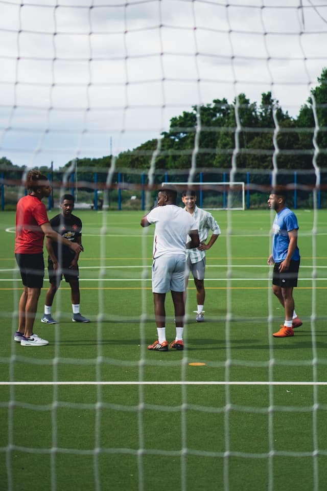 Gruppe Jungs steht auf einem Kunstrasenplatz hinter dem Tornetz